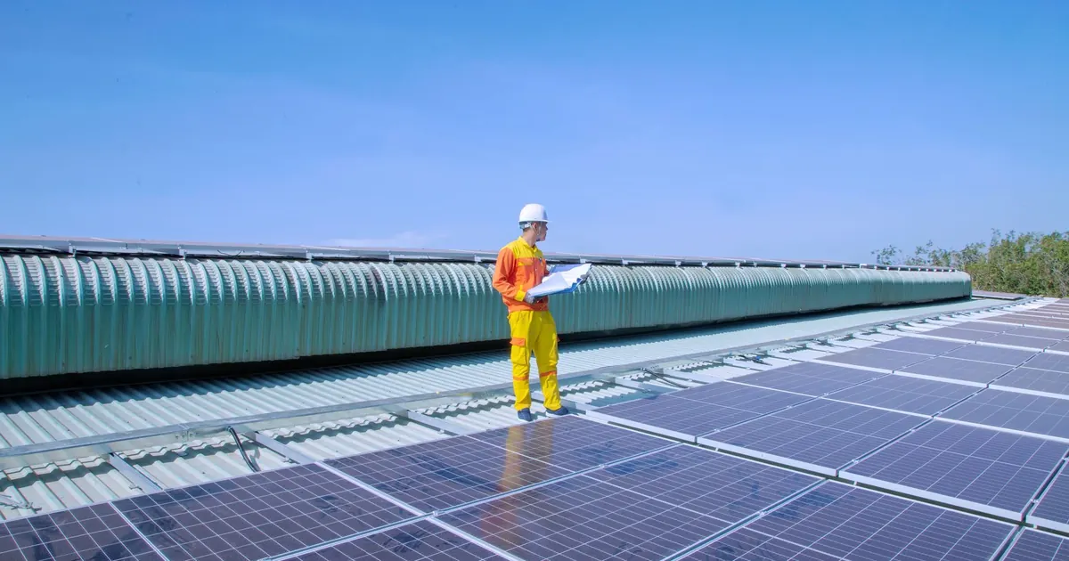 Technicien avec un plan sur une toiture photovoltaïque